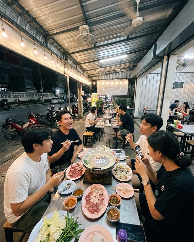 Friends around a sizzling mookata grill