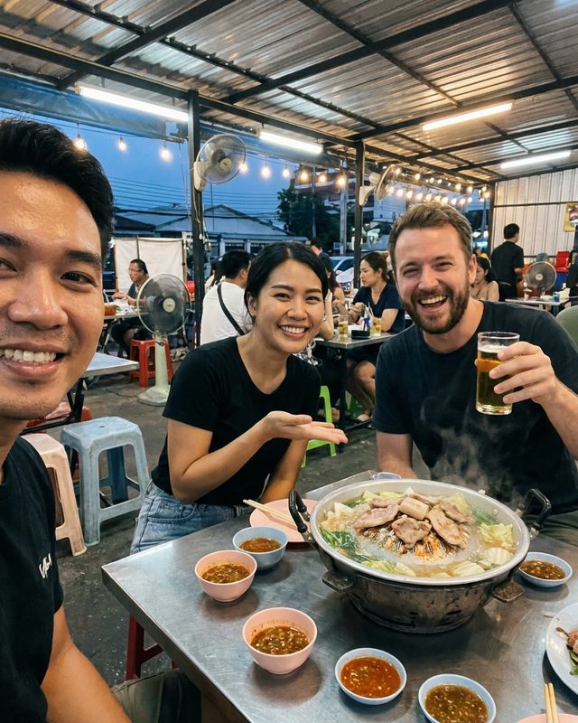 Selfie over a mookata pot at a night-time street restaurant